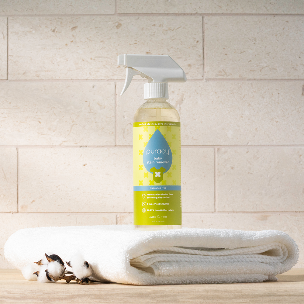 Natural Baby Laundry Stain Remover, 16 Oz, shown on folded white towels beside cotton branches.