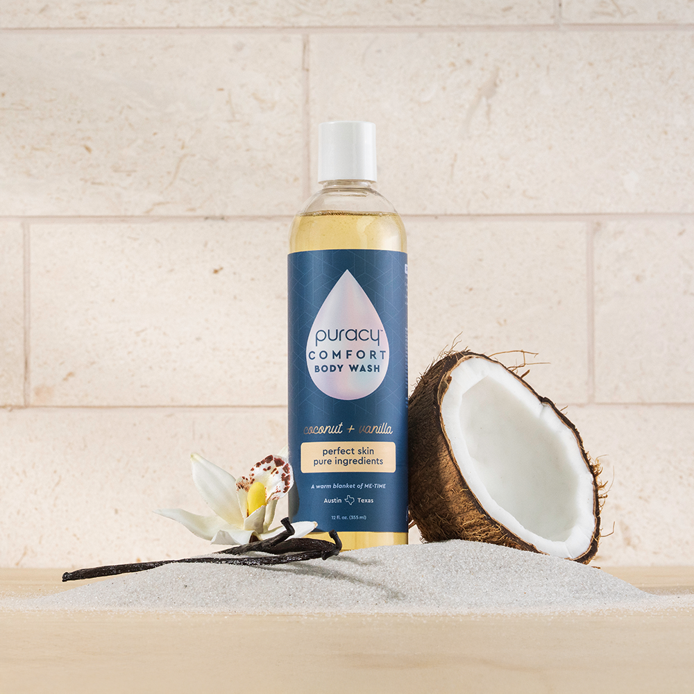 Puracy Body Wash (Acidified, PH Balanced) with coconut cleansers and vanilla beans on sand tiles.