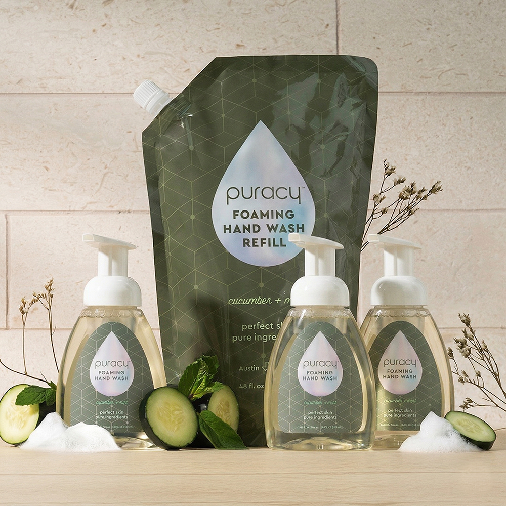 Three Foaming Hand Soap bottles and a refill pouch, with cucumbers and soap suds nearby.
