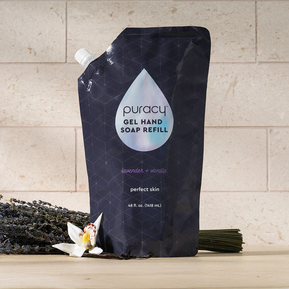 A pouch of Gel Hand Soap refill sits on a table with lavender and vanilla flowers.