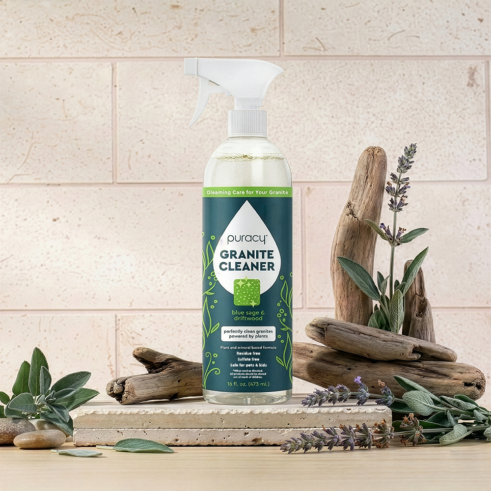 A bottle of Granite Cleaner for natural stone stands by driftwood and sage, safe for daily use.