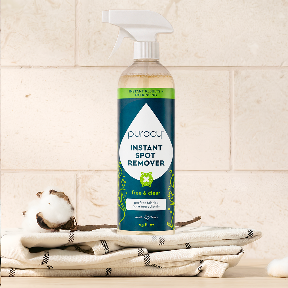 A bottle of Instant Spot Remover rests on folded towels with cotton against a tiled background.
