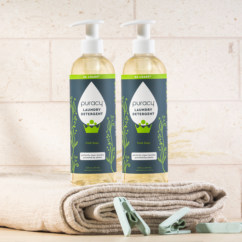 Two bottles of concentrated, sulfate-free laundry detergent on folded towels with clothespins in front.