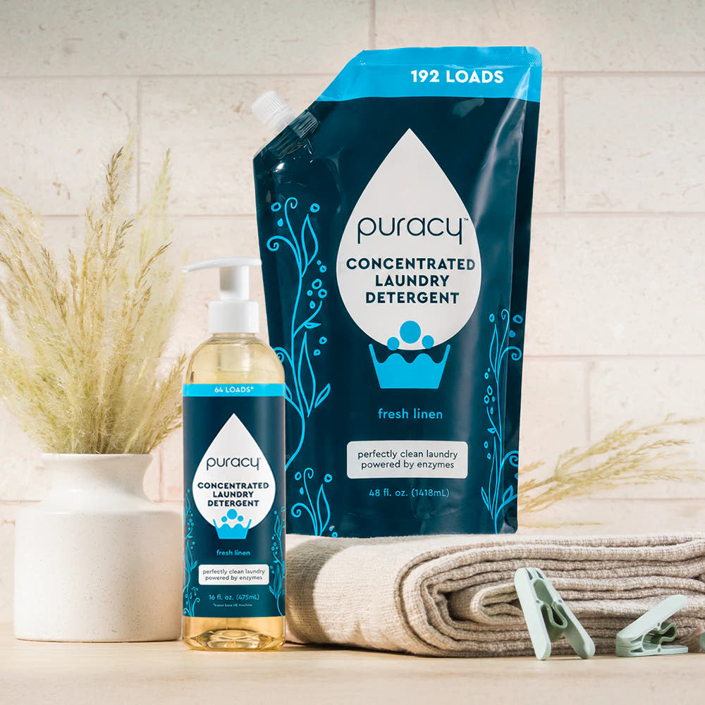 Laundry Detergent (Concentrated, Sulfate-Free) bottles with towels, clothespins, and dried grasses vase.