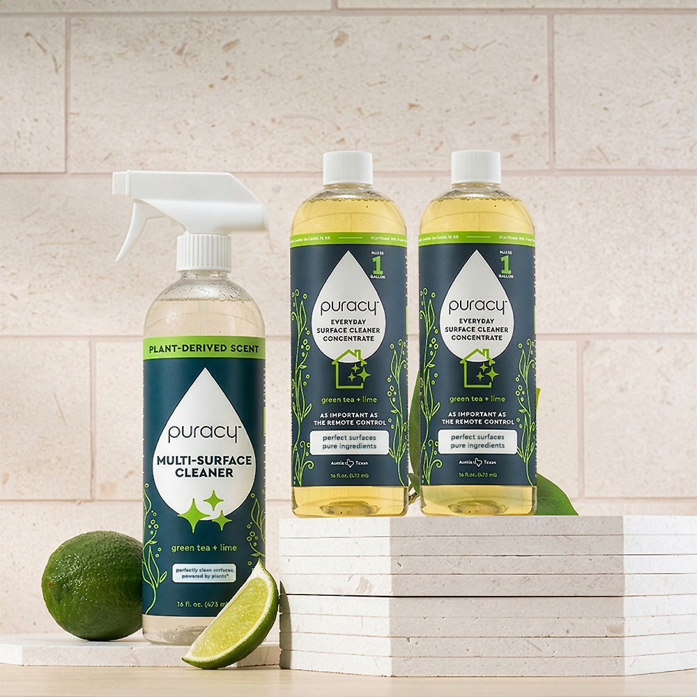 Puracy Multi-Surface Cleaner Spray and a sliced lime on white tiles against a light-colored wall.