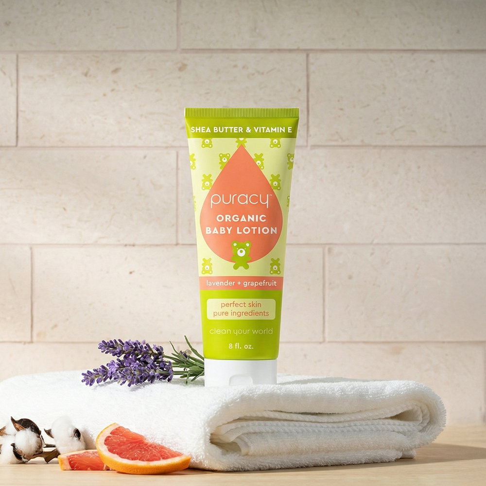 Tube of Organic Baby Lotion on a towel with lavender, grapefruit, and cotton—a baby skincare must-have.