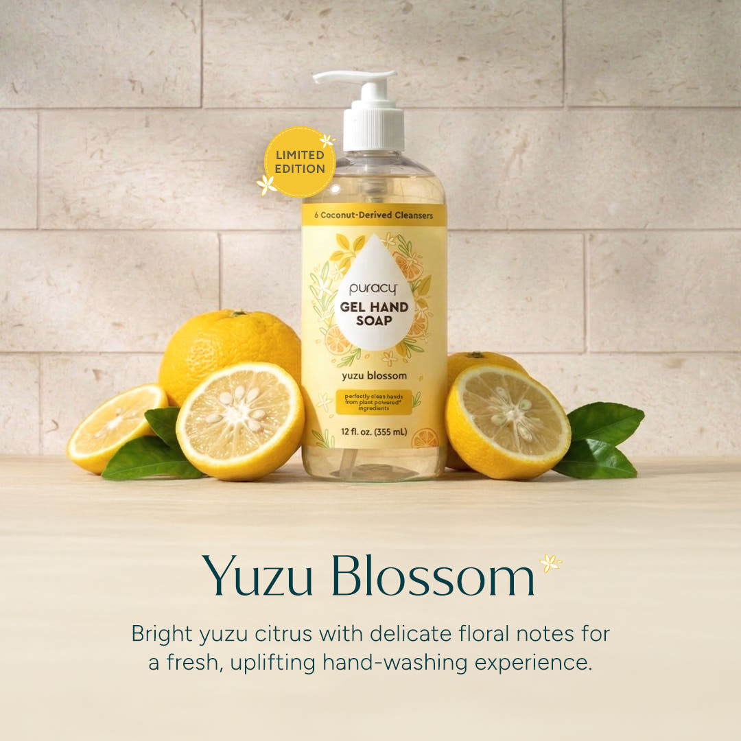 A bottle of Gel Hand Soap with fresh yuzu fruits and green leaves sits on a counter. #common #scent_yuzu-blossom