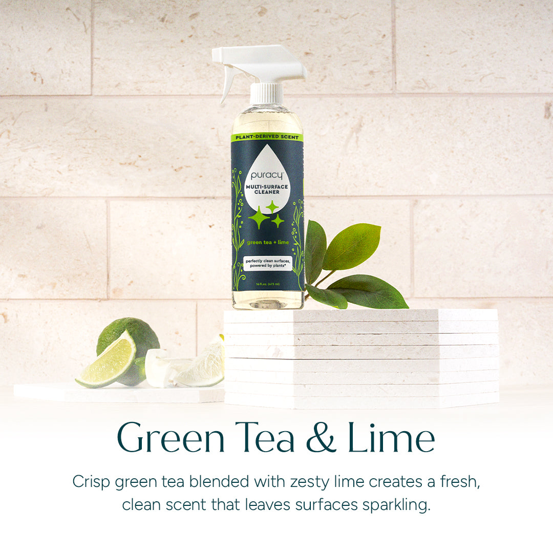 Bottle of Multi-Surface Cleaner Spray with green tea and lime, surrounded by lime slices and leaves.