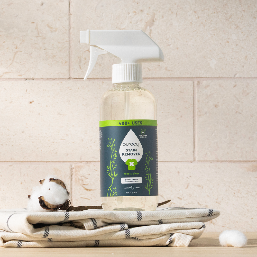 A Laundry Stain Remover sits on folded towels, highlighting its powerful stain-fighting action.