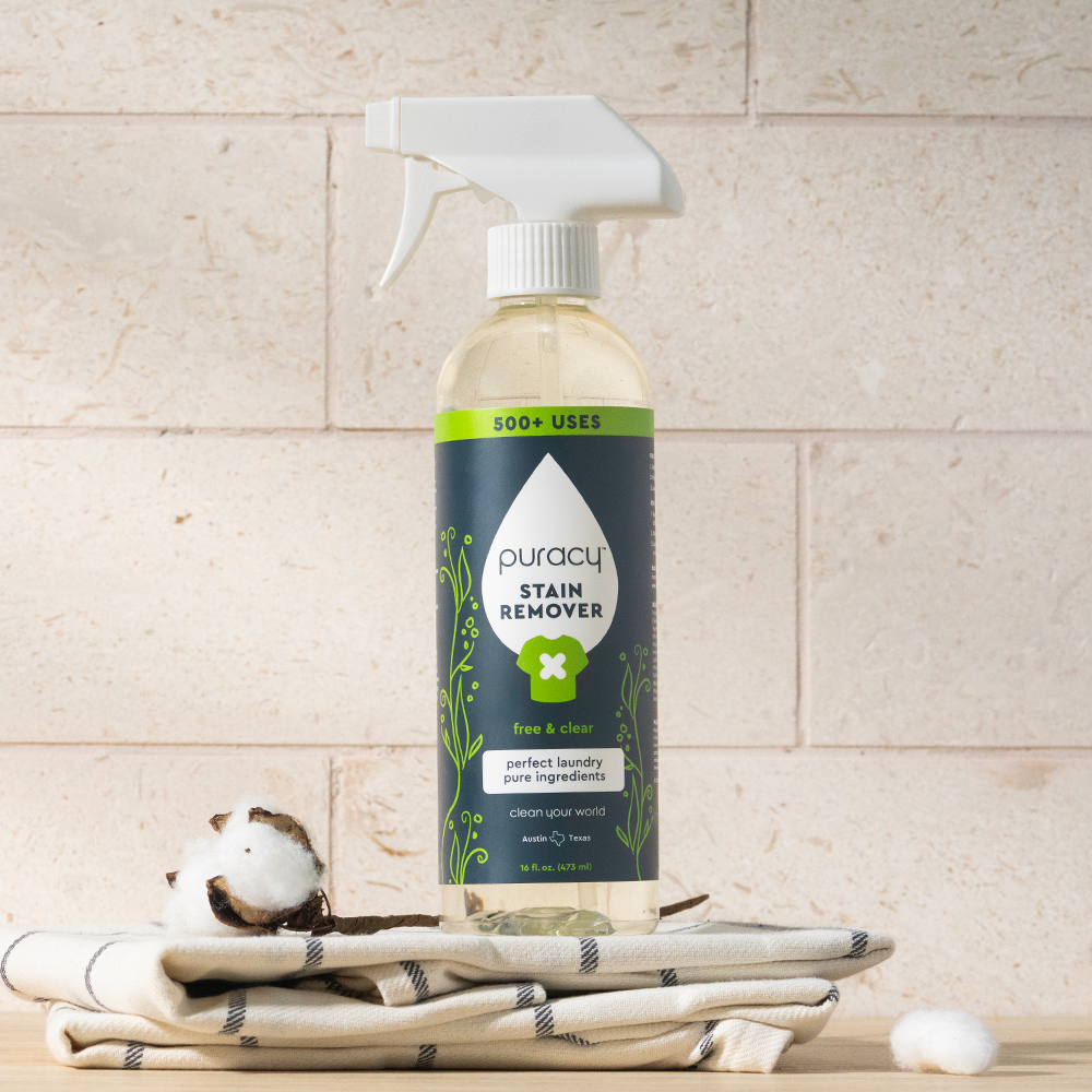 Laundry Stain Remover spray bottle on folded towels and cotton, with a tiled background.