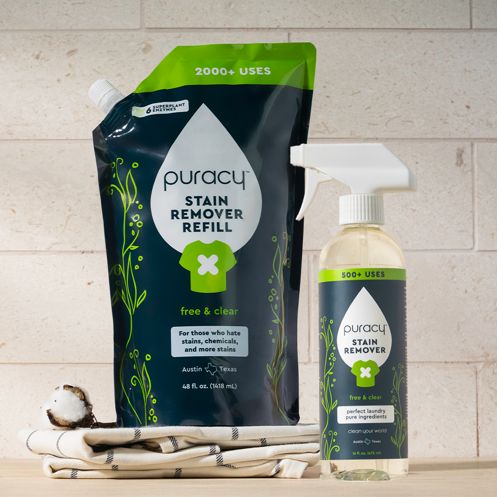 Laundry Stain Remover refill pouch and spray bottle on striped cloth next to a cotton boll.