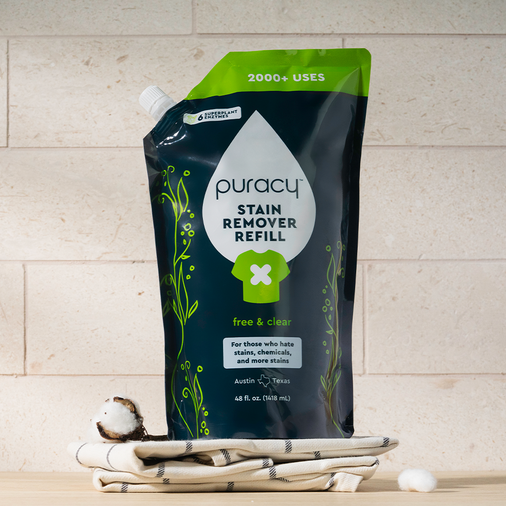 A Laundry Stain Remover refill pouch on folded towels, with a cotton boll nearby.