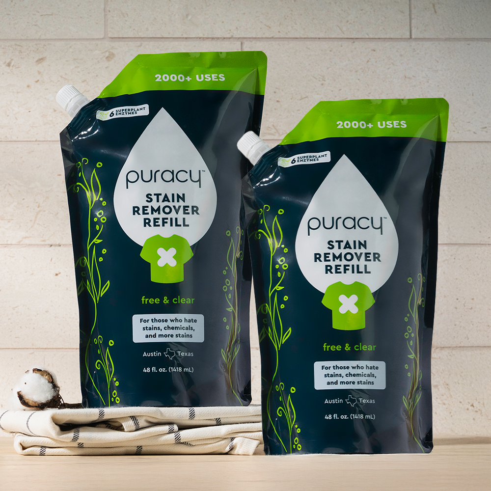 Two hypoallergenic Laundry Stain Remover refill pouches on cloth, cotton, against a light background.