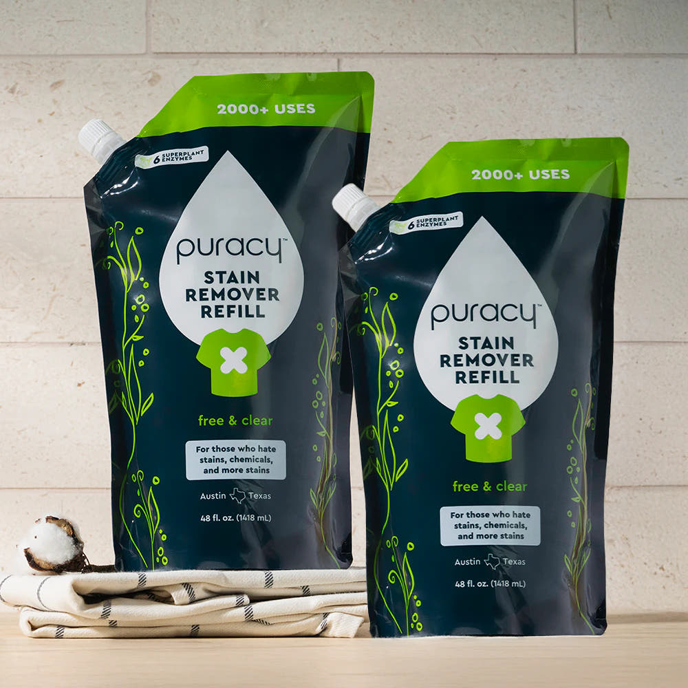 Two Laundry Stain Remover refill pouches on a towel with a cotton boll in front.
