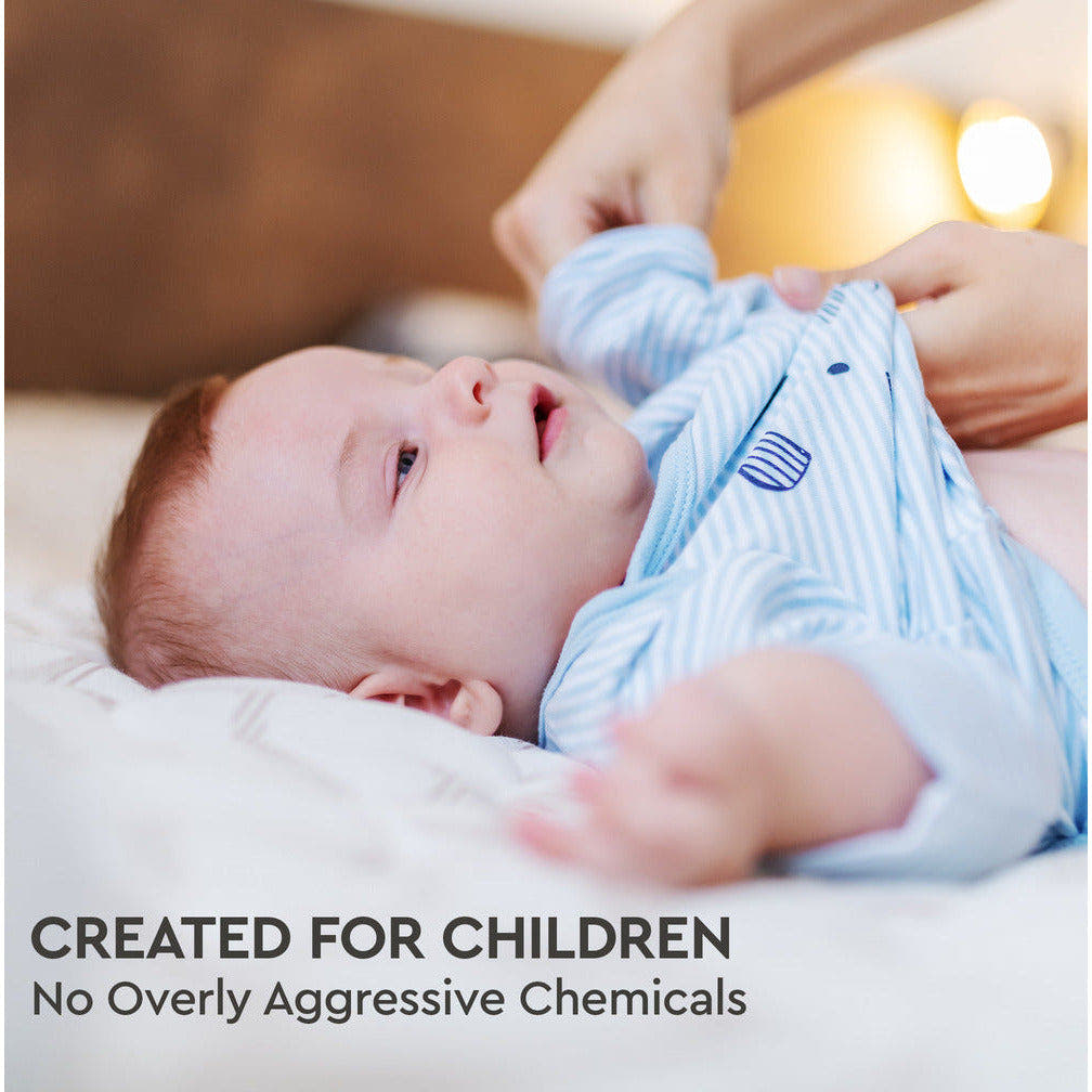 A baby in a striped outfit being dressed, accompanied by the text: Designed for Kids. Free from Harsh Chemicals. Experience hypoallergenic cleanliness with our Natural Baby Laundry Stain Remover and Enzyme Odor Eliminator, ensuring your baby's comfort and safety.