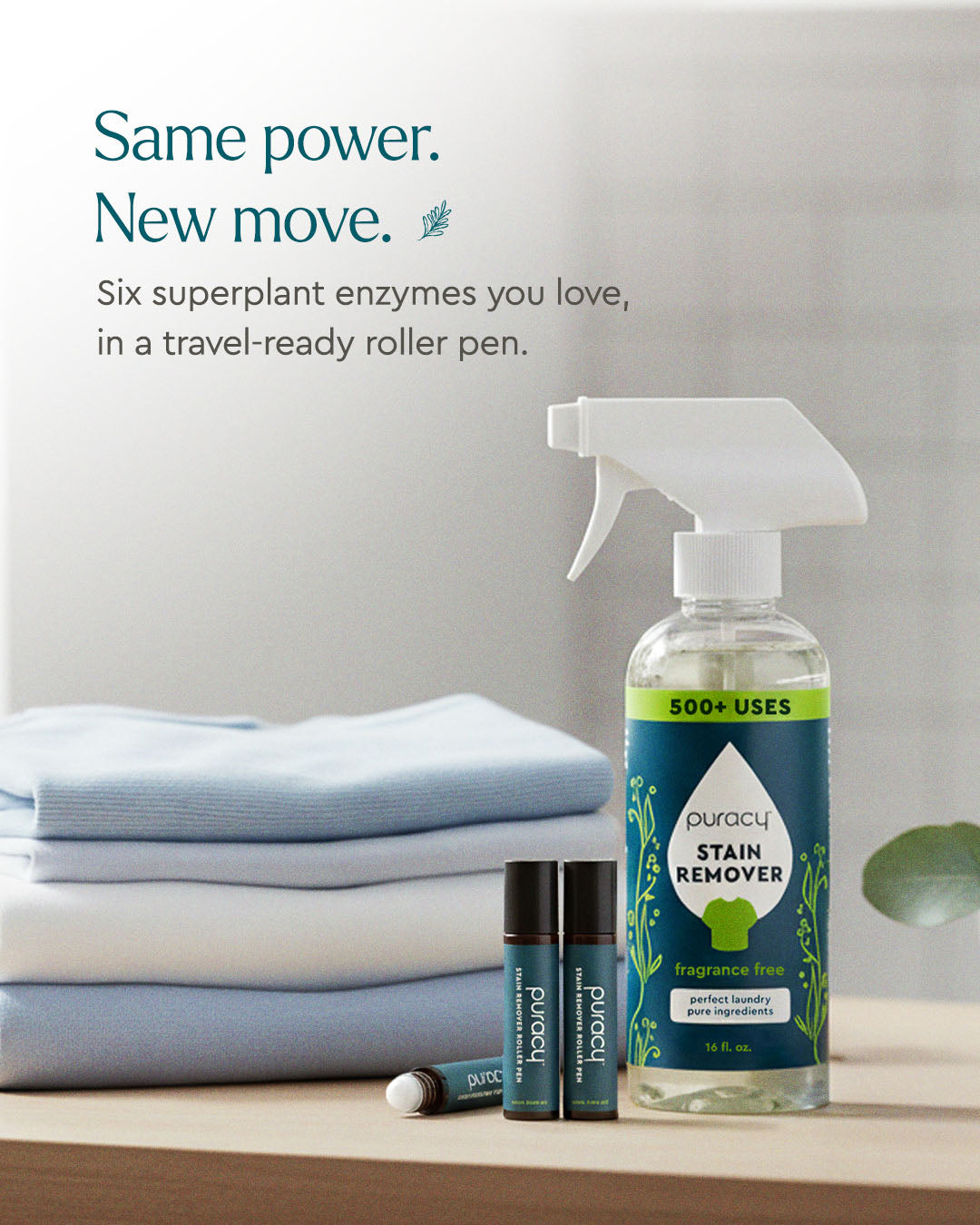 A spray bottle of Laundry Stain Remover and two roller pens beside folded blue and white clothes.