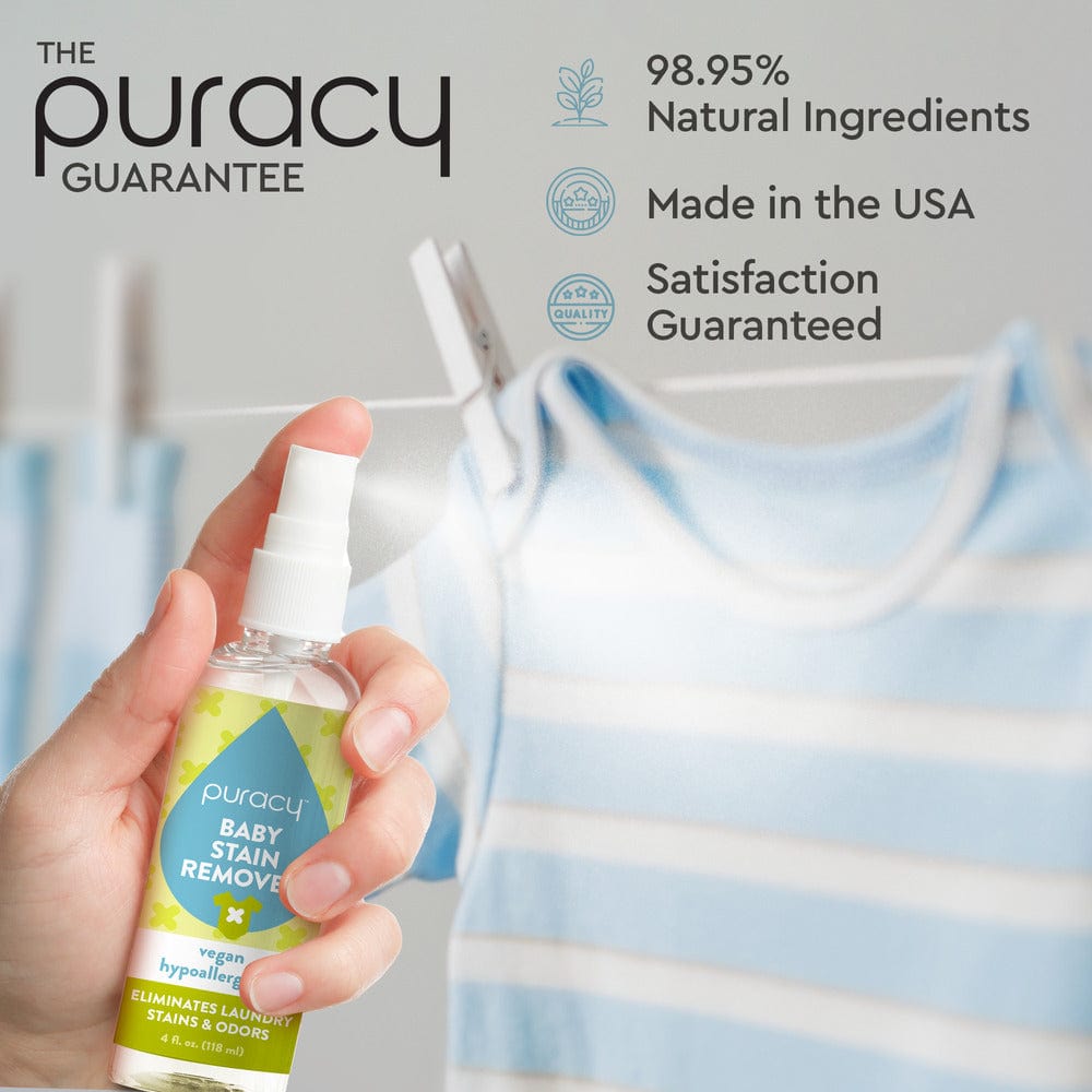 Hand holding the Baby Stain Remover spray featuring plant-based enzymes near a striped baby outfit on a clothesline.