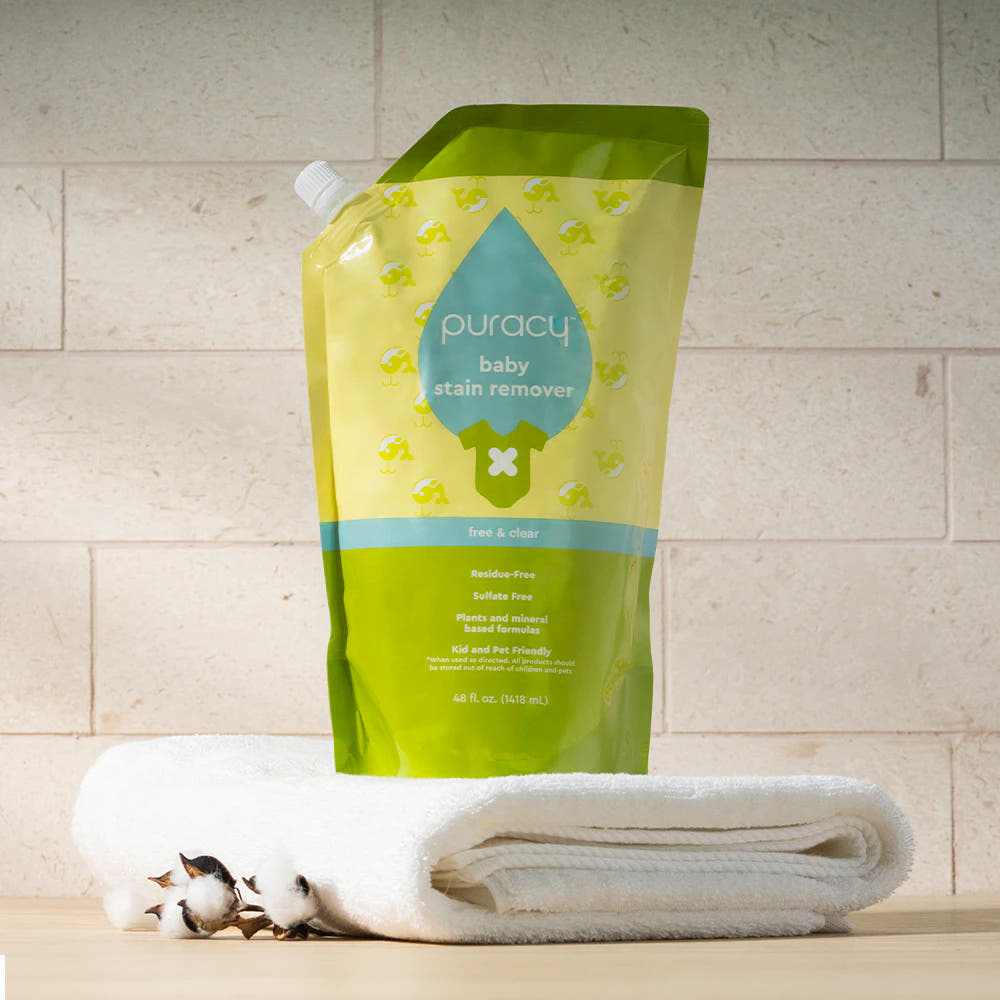 A pouch of Baby Stain Remover on a folded white towel with cotton bolls beside it.