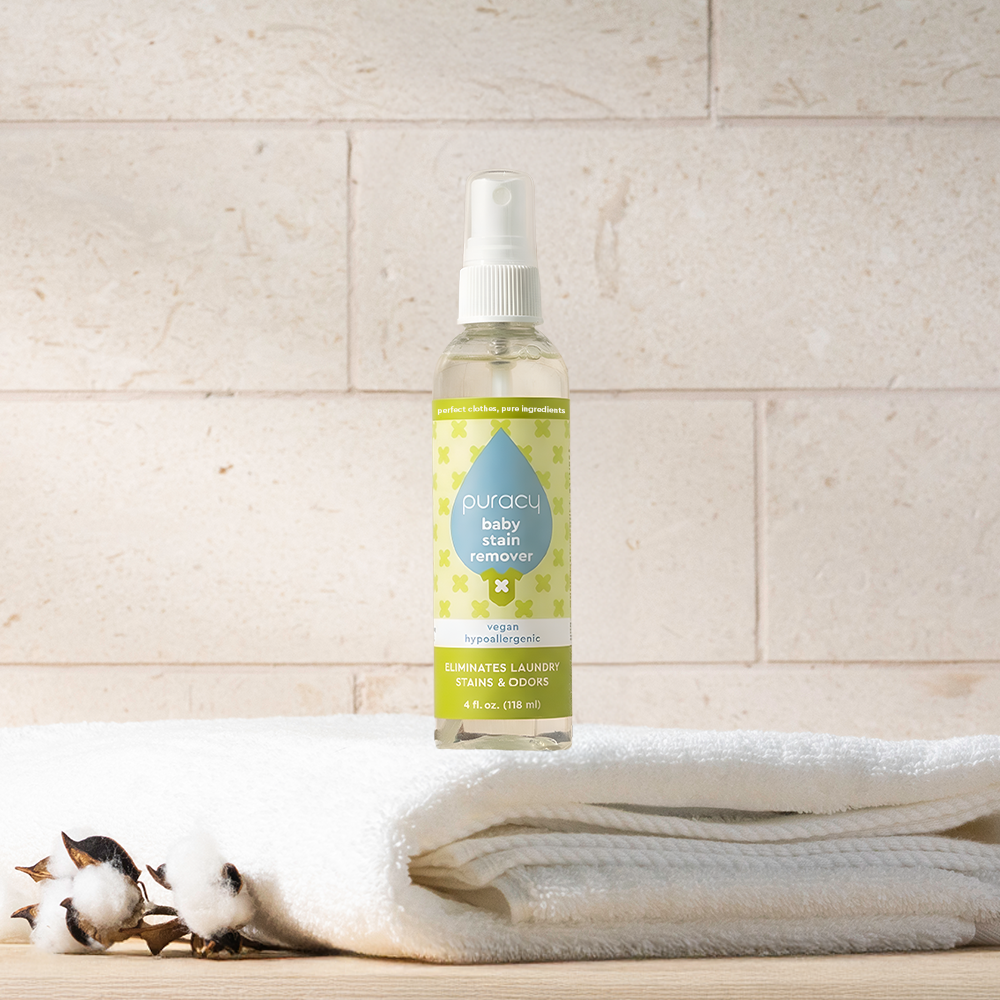 Baby Stain Remover bottle on folded white towels, with cotton flowers nearby.