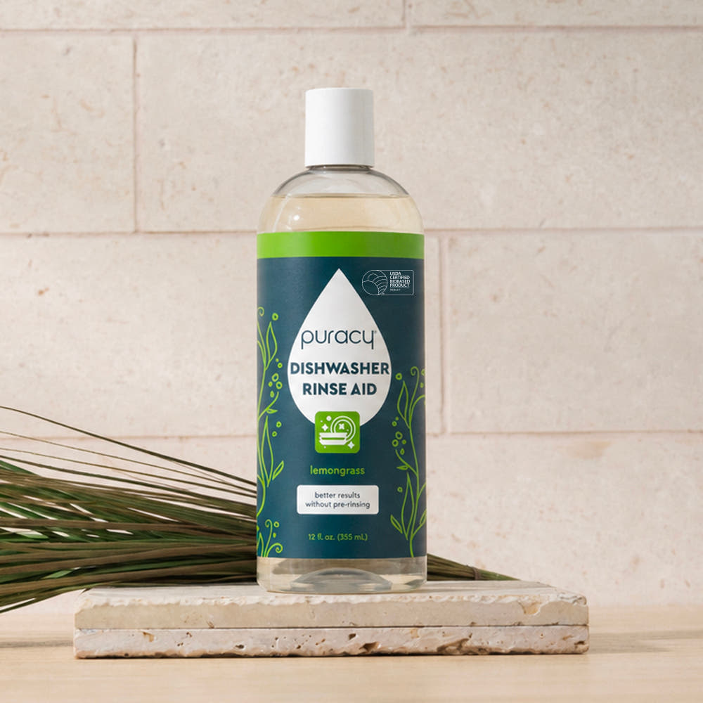 A bottle of Dishwasher Rinse Aid in lemongrass scent on a white tile surface.