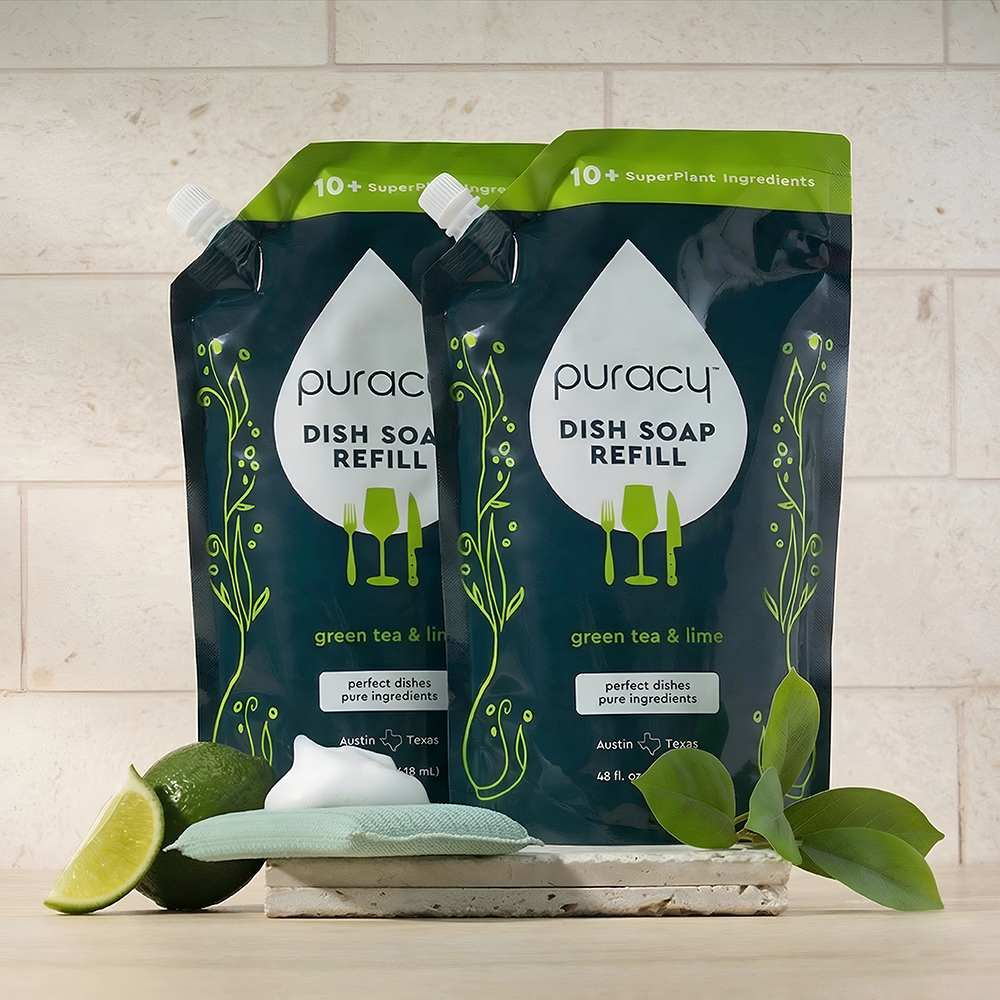 Two Puracy Dish Soap refill pouches, green tea & lime scent, with a lime and green leaves beside them.