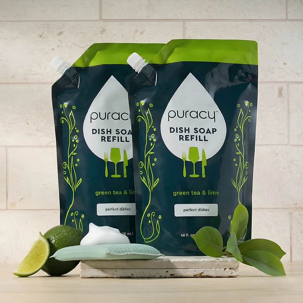 Two eco-friendly Dish Soap refill pouches with green tea & lime, surrounded by limes and leaves.