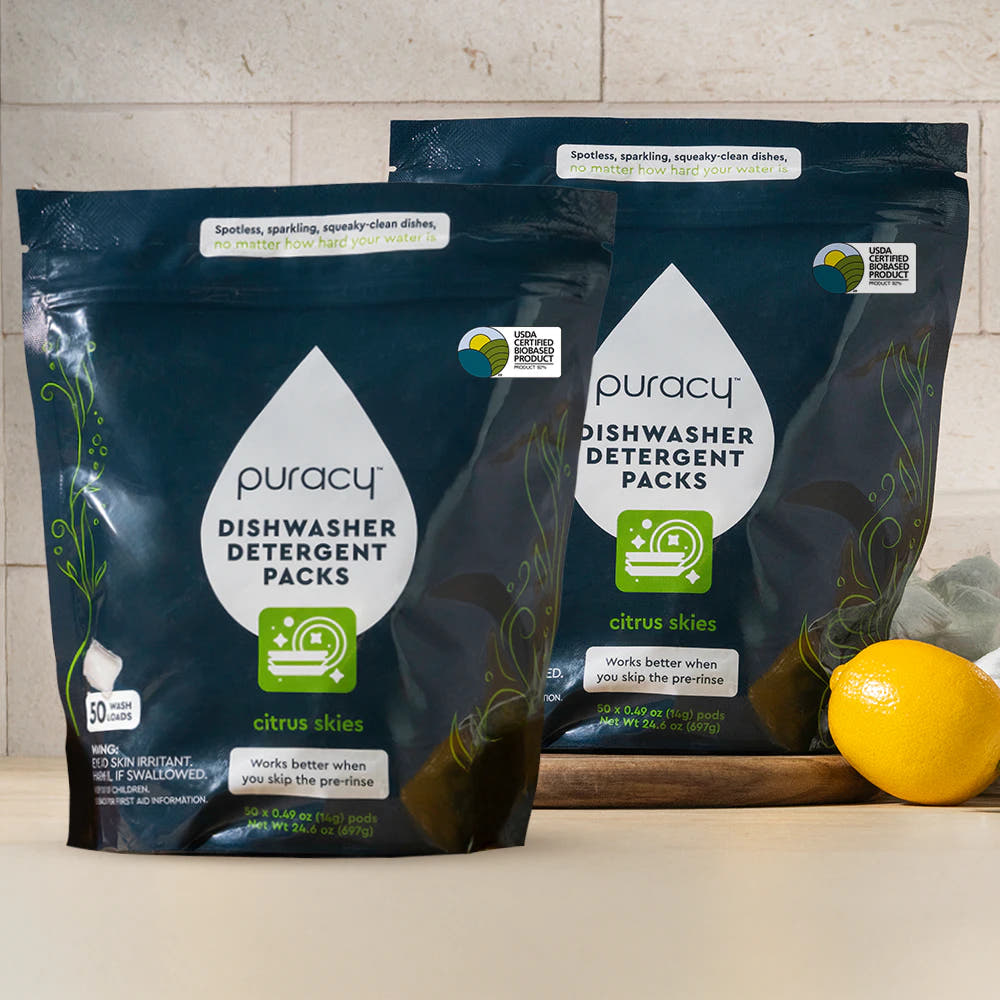 Two bags of Dishwasher Detergent Pods, citrus scent, on a counter with a lemon nearby.