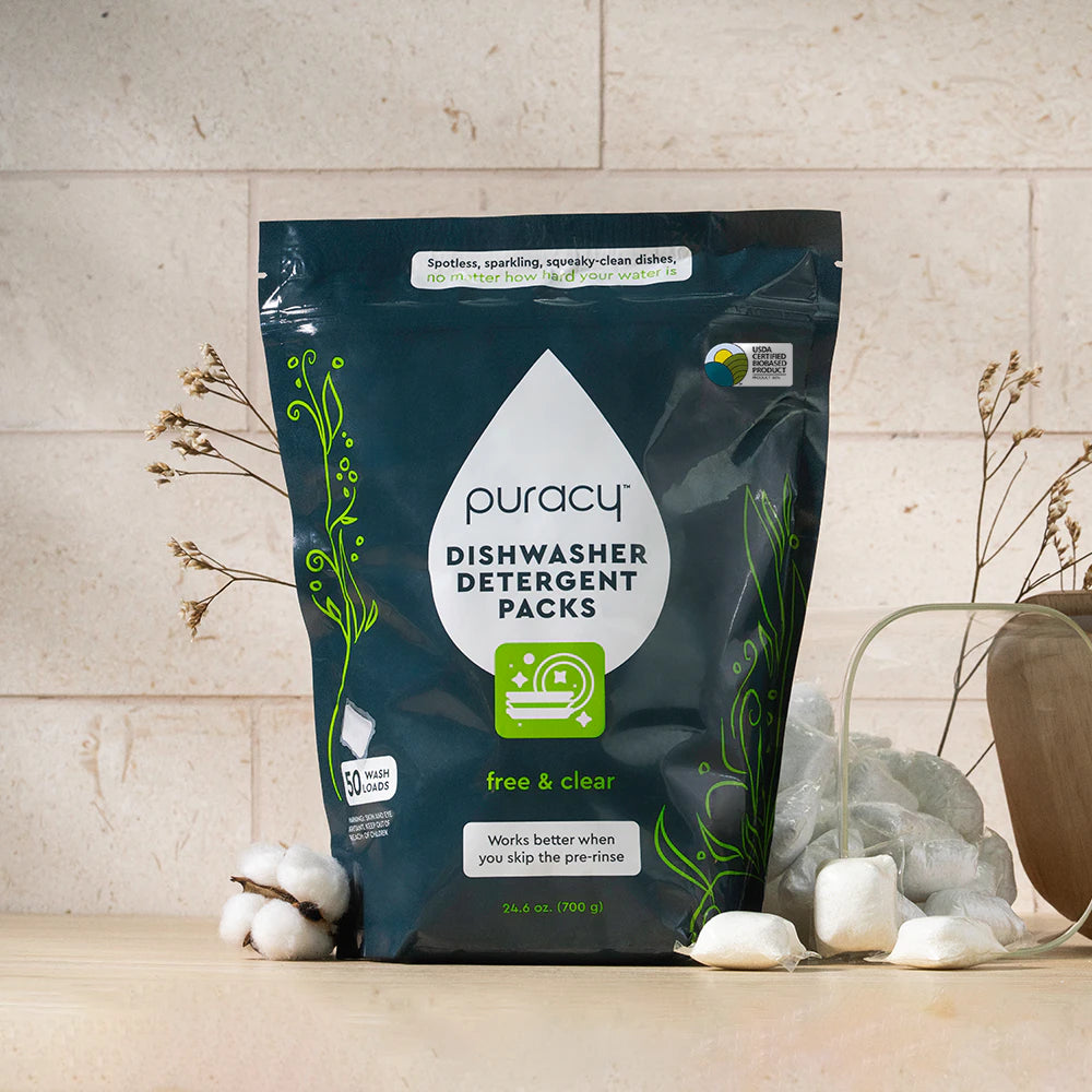 A bag of Dishwasher Detergent Pods sits on a counter with cotton and dried flowers beside it.