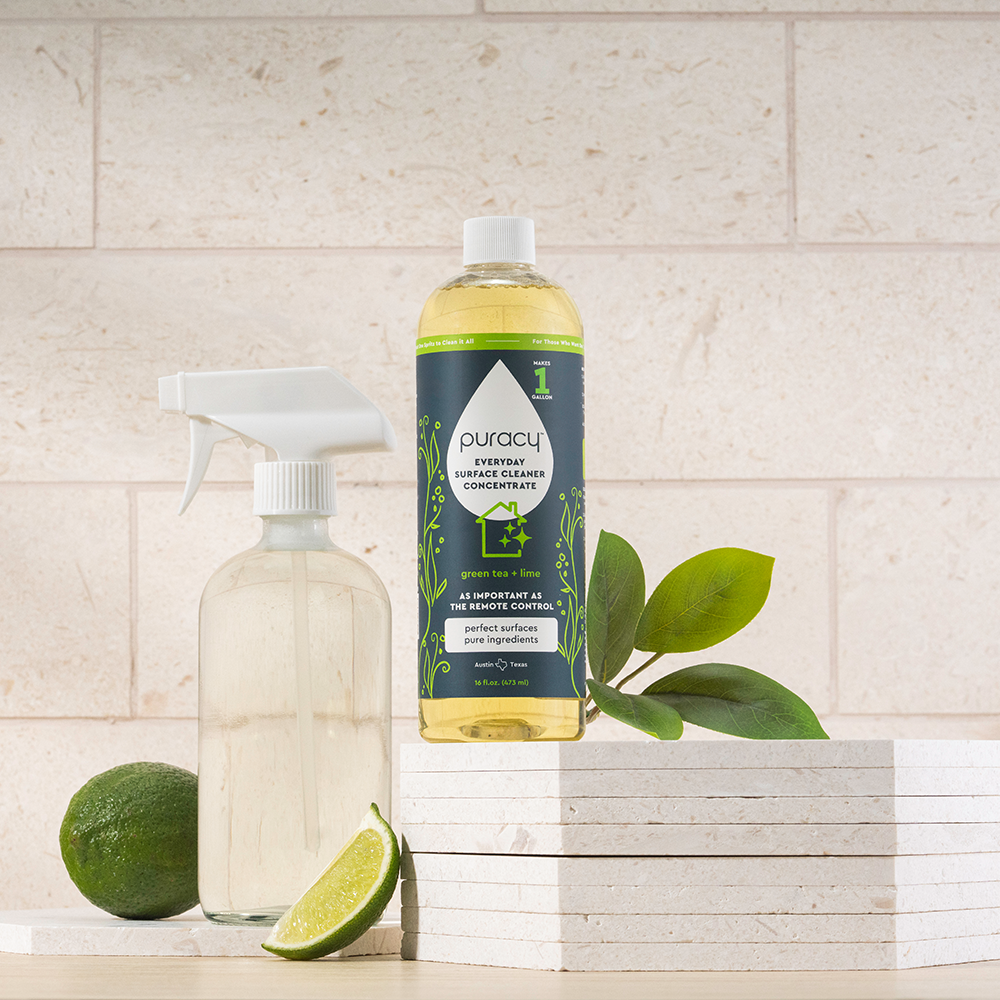 Everyday Multi-Surface Cleaner bottle with lime, green leaves, and spray bottle on stacked tiles.