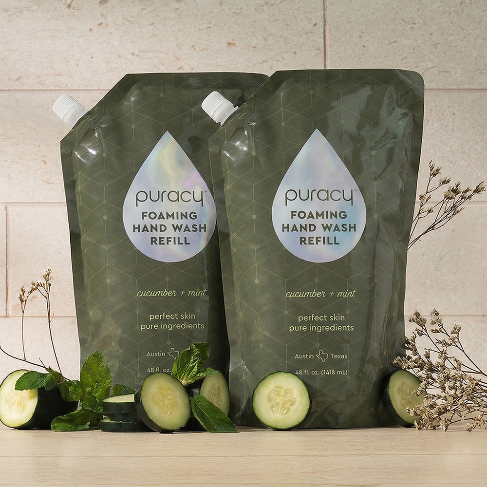 Two Foaming Hand Soap refill pouches with cucumber, mint, and dried flowers nearby.