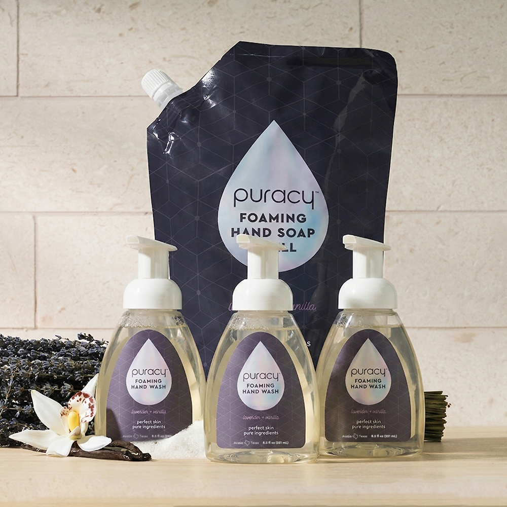 Three Foaming Hand Soap bottles and a refill pouch, with lavender and vanilla flowers nearby.
