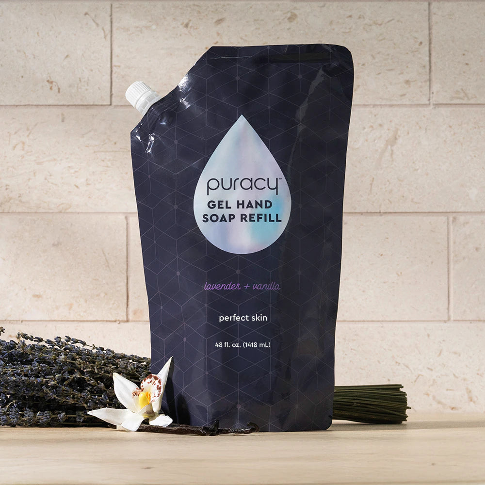 A pouch of Gel Hand Soap refill sits on a table with lavender and vanilla flowers.