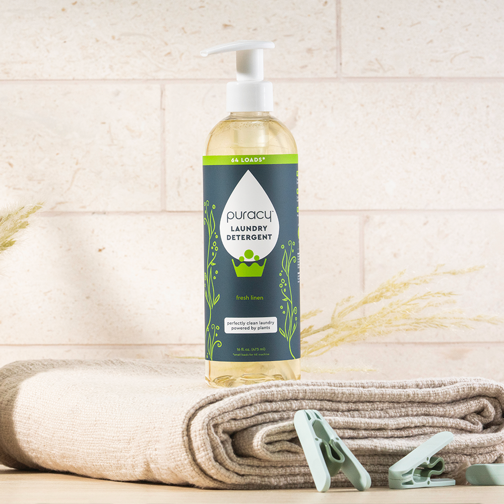 A bottle of eco-friendly Laundry Detergent (Concentrated, Sulfate-Free) on towels with clothespins.