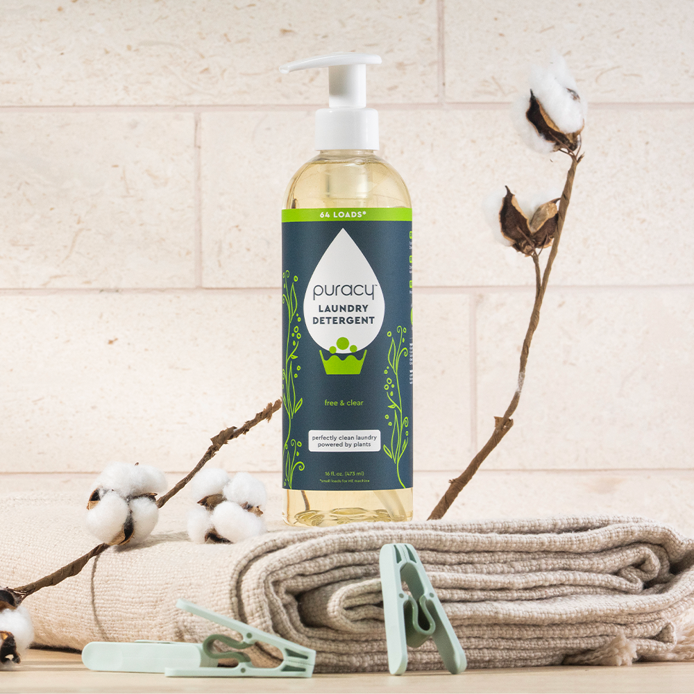 A bottle of Laundry Detergent (Concentrated, Sulfate-Free) on folded towels with cotton branches nearby.