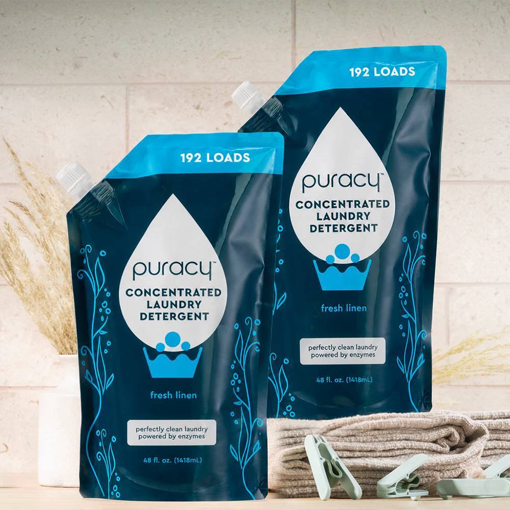 Two blue Laundry Detergent (Concentrated, Sulfate-Free) pouches beside folded towels and clothespins.