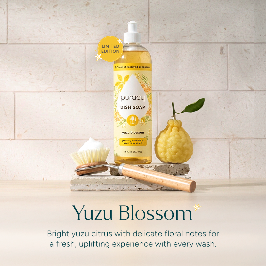 A bottle of Dish Soap with a brush, sponge, and yuzu fruit on a stone surface. #common #scent_yuzu-blossom standard-pack-of-3_#size