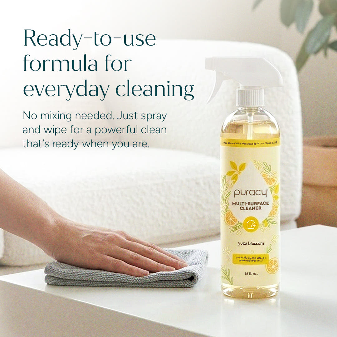 A hand wipes a table beside Multi-Surface Cleaner Spray, plant-powered and yuzu blossom scented.