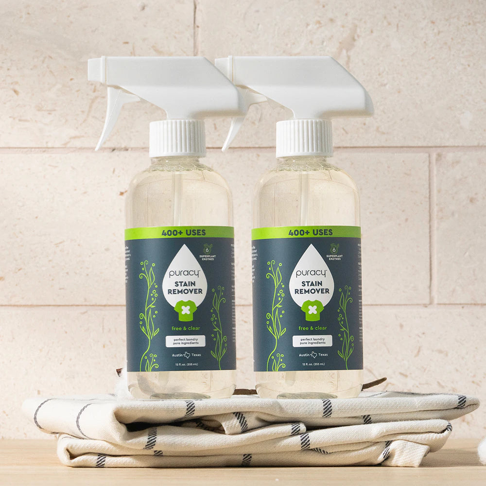 Two bottles of Laundry Stain Remover on a folded cloth, set against a light brick background.